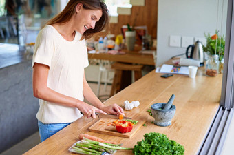 烹饪进步有吸引力的年轻的女人切蔬菜厨房