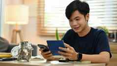 快乐年轻的亚洲男人。聪明的电话使在线支付管理费用财务状况生活房间