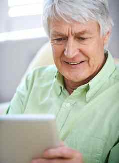 阅读新闻在线上了年纪的男人。数字平板电脑坐着沙发首页