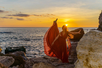 跳舞女人红色的飞行衣服海洋海海滩背景日落天空