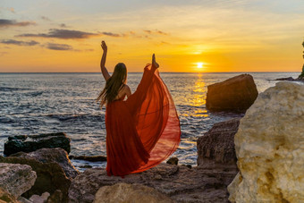 跳舞女人红色的飞行衣服海洋海海滩背景日落天空