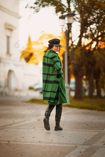 户外时尚肖像优雅的时尚浅黑肤色的女人女人模型时尚的帽绿色衣服摆姿势日落欧洲城市秋天