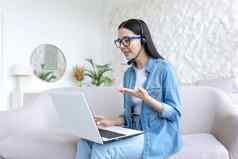 在线工作年轻的自由职业者女人坐着首页工作移动PC耳机在线