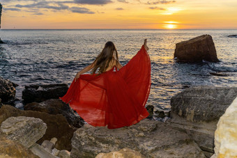 跳舞女人红色的飞行衣服海洋海海滩背景日落天空