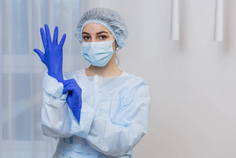 年轻的女医生准备手术穿蓝色的外科手术手套白色外套面具相机