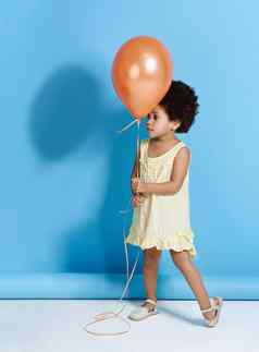 跳舞气球可爱的女孩持有气球蓝色的背景