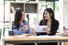 漂亮的年轻的亚洲女商人坐着桌子上移动PC文书工作讨论项目金融报告企业业务协作概念