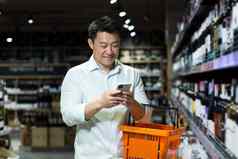 快乐亚洲购物者超市智能手机应用程序选择扫描酒