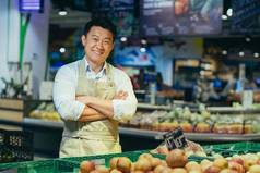 肖像快乐英俊的亚洲推销员蔬菜水果市场杂货店商店卖方男人。围裙相机微笑农民小业务老板蔬菜水果商