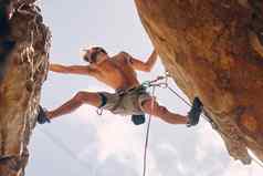 健身岩石攀爬强大的山登山者悬崖绳子夏天挑战极端的锻炼危险勇气健康的男人。无所畏惧的体育大岩石石头视图