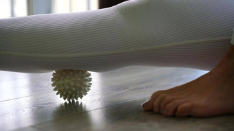 运动苗条的高加索人女人大腿自我按摩按摩球在室内self-isolating按摩
