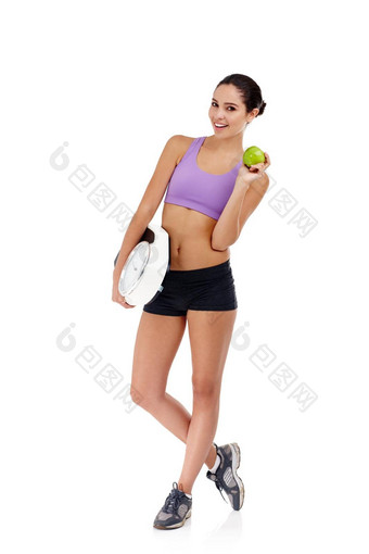 锻炼健康的吃=减肥法工作室拍摄有吸引力的年轻的女人穿着健身房衣服持有苹果重量规模
