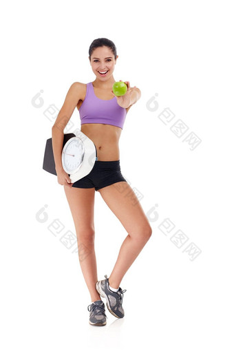 健康的吃部分<strong>减肥</strong>法程序工作室拍摄有吸引力的年轻的女人穿着<strong>健身</strong>房衣服持有苹果重量规模