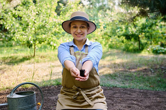 令人愉快的可爱的女人农民农学家微笑将发芽幼苗番茄黑色的地球相机