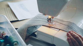 特写镜头现代电缝纫机工作缝合一块纺织女孩的修剪整齐的手色彩斑斓的缝纫线程可见