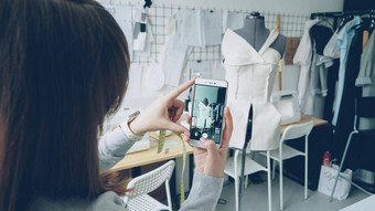 年轻的女服装设计博主拍摄裁剪假半成品的服装固定特写镜头拍摄女孩的手智能手机