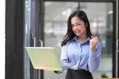 快乐亚洲女商人持有移动PC庆祝成功在线市场营销办公室