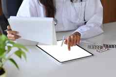 裁剪拍摄女医生白色统一的持有文档检查医疗信息数字平板电脑