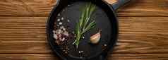 黑色的投铁煎锅长柄平底煎锅食物烹饪成分新鲜的迷迭香大蒜盐胡椒