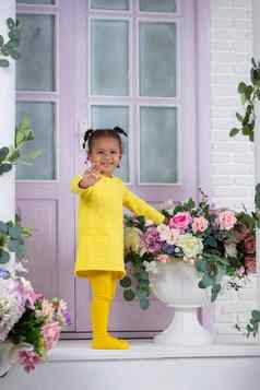 非洲女孩黄色的衣服站玄关房子花