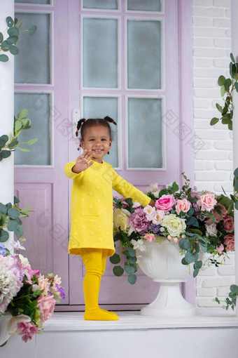 非洲女孩黄色的衣服站玄关房子花