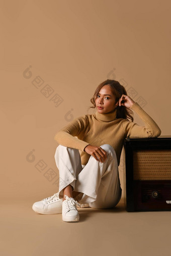 肖像时尚女人穿时尚的毛衣坐着古董广播米色背景秋天时尚概念