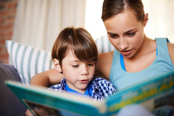 帮助儿子阅读年轻的妈妈。儿子阅读