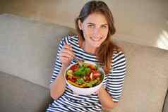 有益健康的健康的年轻的女人吃碗完整的沙拉沙发首页