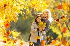 快乐家庭秋天走妈妈。女儿走公园享受美丽的秋天自然
