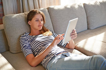 在线休闲年轻的女人数字平板电脑沙发首页