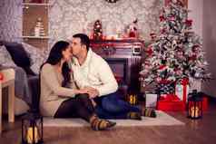 年轻的丈夫接吻妻子额头圣诞节一天前面温暖的壁炉