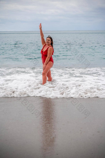 女人洗澡西装海脂肪年轻的女人红色的泳衣进入水冲浪