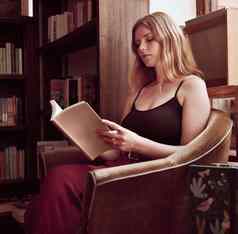 图书馆书女人阅读书书店首页研究放松和平休息无忧无虑的爱好年轻的女孩享受文学有趣的故事坐着