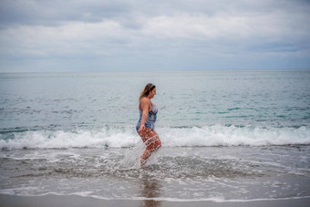 丰满女人洗澡西装进<strong>入水</strong>冲浪海滩灰色的天空云游泳冬天