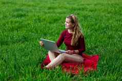 年轻的成功的女人坐着绿色草移动PC手工作自然学生女孩工作隐蔽的的地方业务的想法