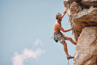 男人。山岩石攀爬悬崖挂肾上腺素运动员冒险检查安全设备钩绳子无所畏惧的男人。健身锻炼锻炼极端的体育运动