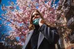 女孩年轻的女人保护无菌医疗面具脸相机在户外春天花园空气污染病毒流感大流行冠状病毒概念