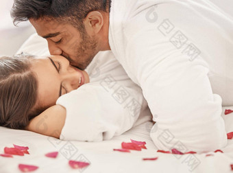 爱吻玫瑰花瓣夫妇床上快乐庆祝订婚度蜜月花浪漫婚姻周年纪念日庆祝活动男人。女人浪漫的假期