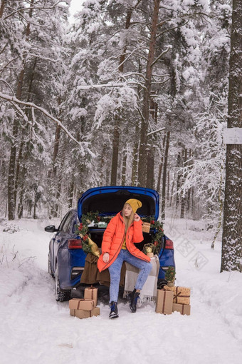 女人冬天白雪覆盖的森林树干蓝色的车装饰圣诞节装饰概念圣诞节冬天假期