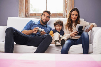 时间家庭时间花了儿子父亲玩视频游戏妈妈。读取杂志
