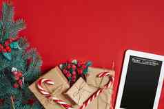 冷杉分支礼物盒子白色平板电脑黑色的屏幕红色的背景