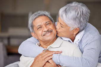 快乐墨西哥高级夫妇吻生活房间沙发<strong>爱护</strong>理信任浪漫的的关系房子首页上了年纪的人退休男人。女人微笑拥抱接吻脸脸颊