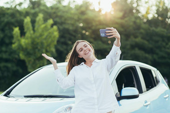 美丽的年轻的女人买了车微笑快乐会说话的电话分享朋友新闻购买车