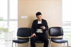 年轻的成功的亚洲男人。等待工作面试等待房间办公室中心坐着椅子接待办公室中心