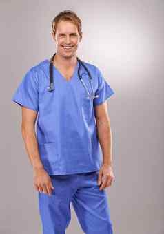 一流的手术技能工作室肖像英俊的医生站灰色的背景
