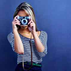 时髦的摄影师年轻的女人采取图片相机