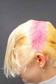 年轻的高加索人女人调头发根粉红色的颜色美沙龙