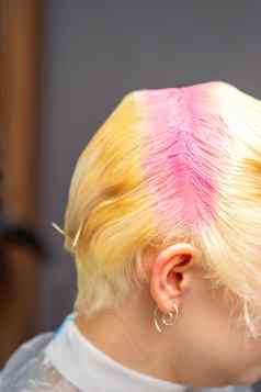 年轻的高加索人女人调头发根粉红色的颜色美沙龙