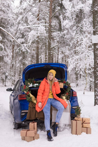 女人冬天白雪覆盖的森林树干蓝色的车装饰圣诞节装饰概念圣诞节冬天假期