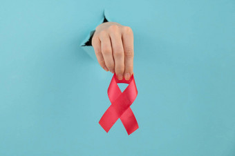 女人的手红色的弓棒洞蓝色的背景象征战斗艾滋病